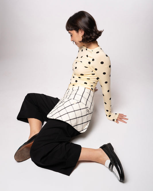 Person wearing a polka dot top and black pants on a white background