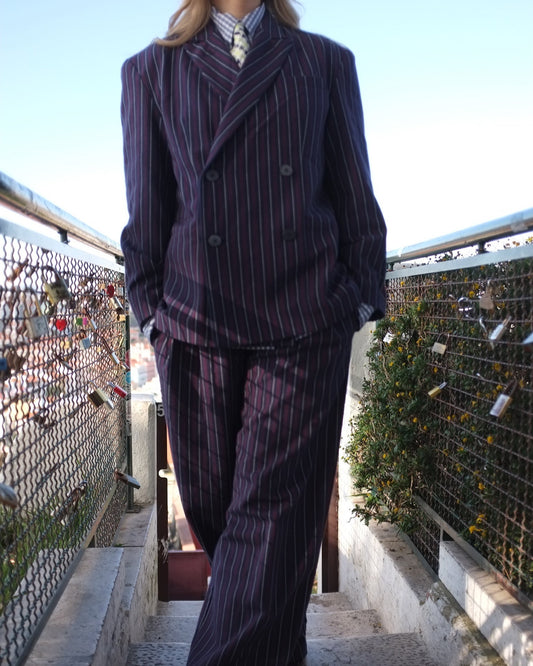 Person wearing a pinstripe suit standing on a bridge with a scenic background