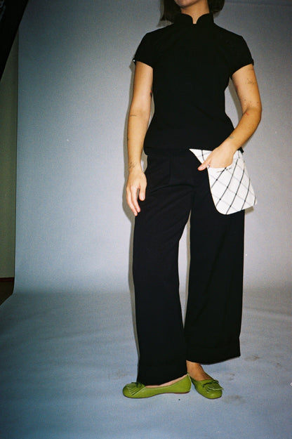 Person wearing a black outfit with green shoes on a plain background