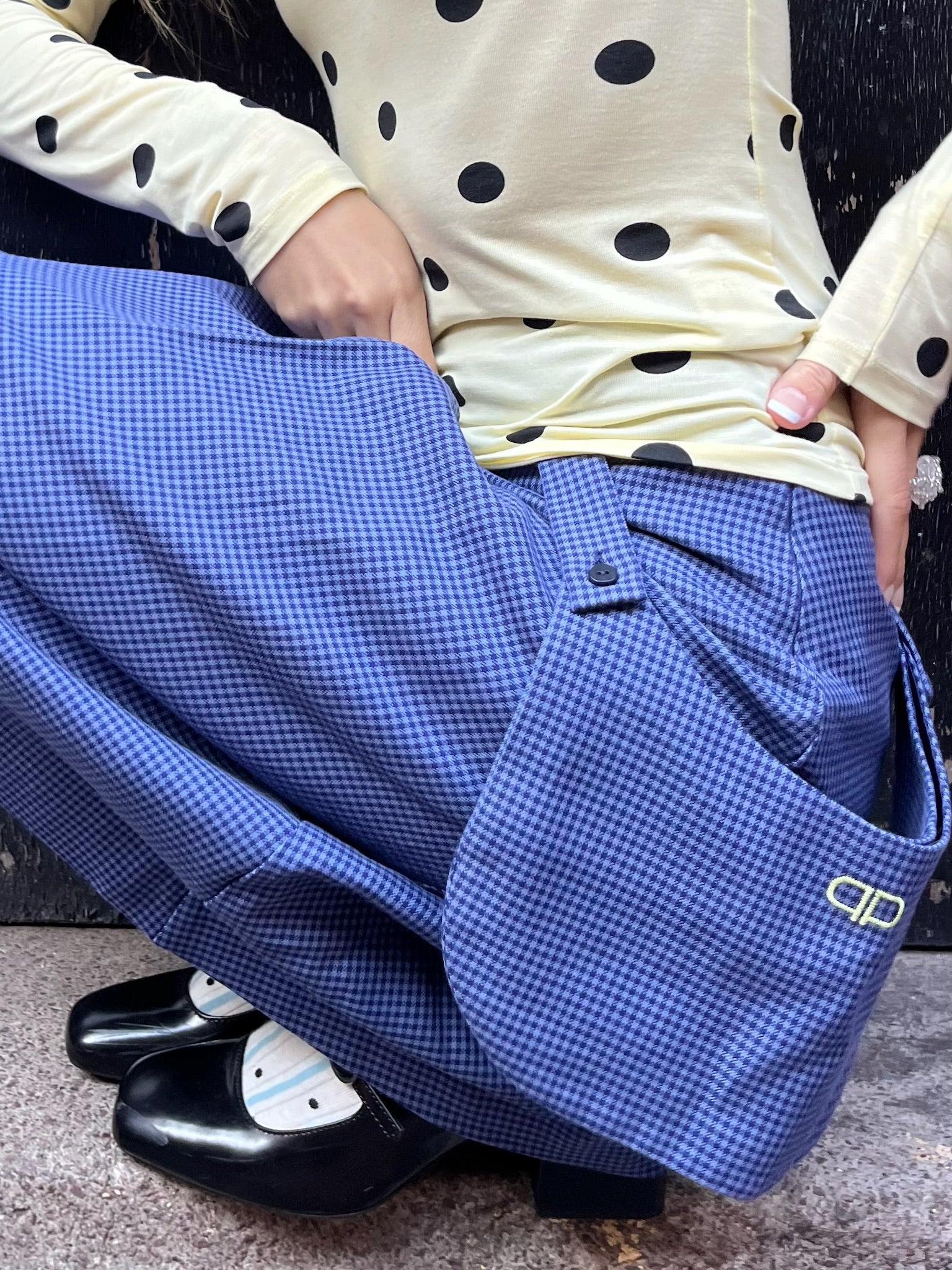 Person wearing blue checkered skirt with a visible brand logo