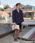 Person standing on a rooftop with a cityscape background wearing a striped suit jacket