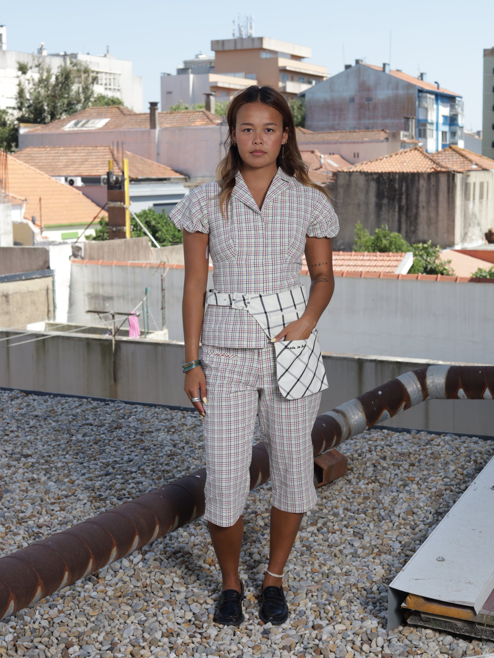 Woman standing on a rooftop with buildings and sky in the background