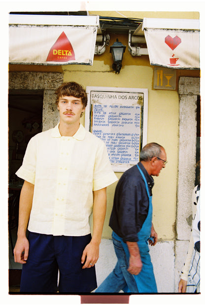 Man in a butter yellow shirt and navy shorts.