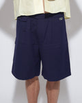 Person wearing navy shorts and a light yellow shirt on a white background