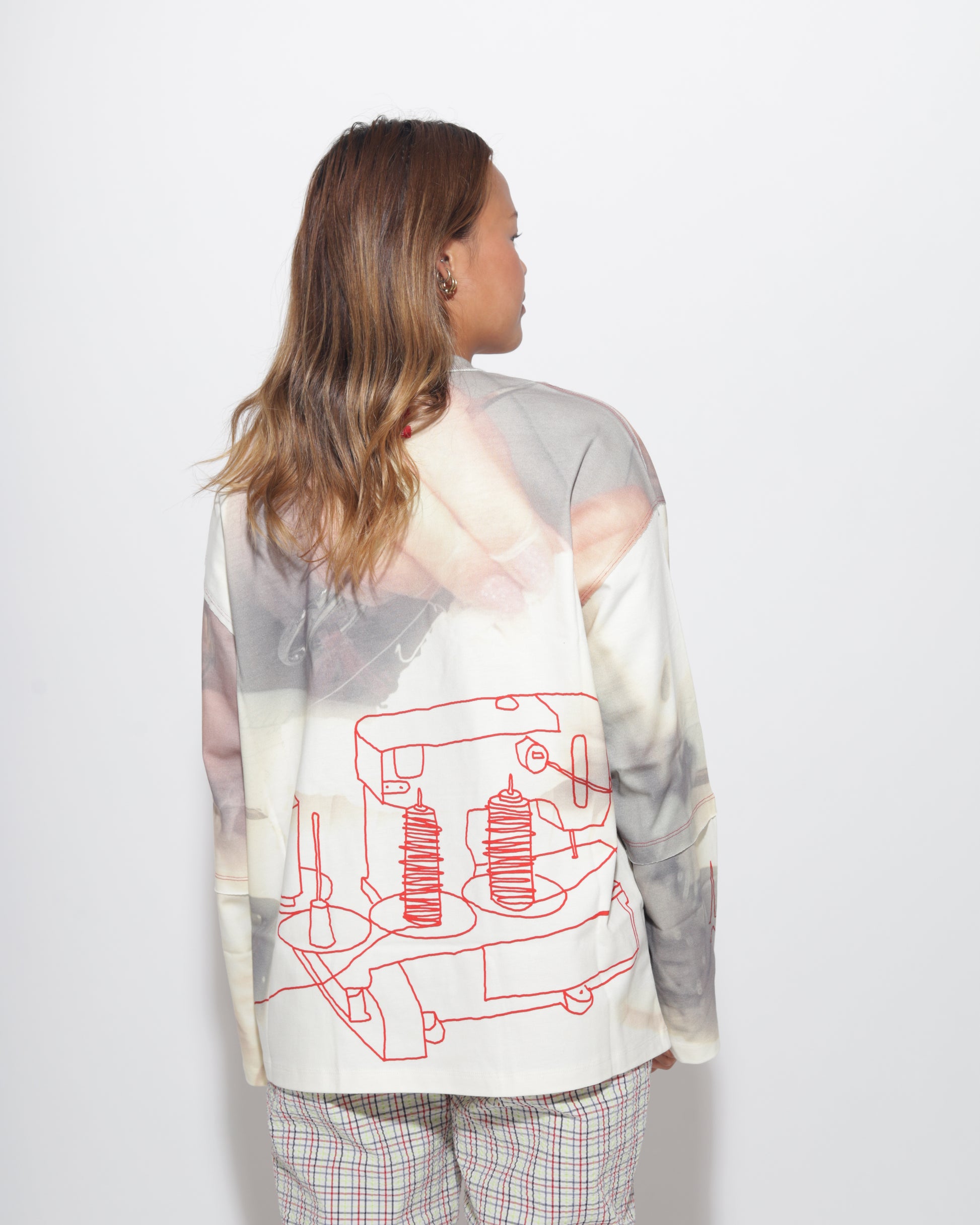 Person wearing long sleeve t-shirt with a red graphic design on a white background