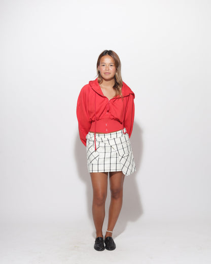 Person wearing a red hoodie and plaid skirt on a white background