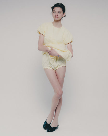 Person wearing a yellow dress on a plain background