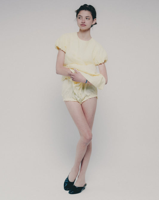 Person wearing a yellow dress on a plain background