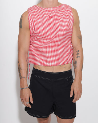 Person wearing a red checkered vest and black shorts on a white background