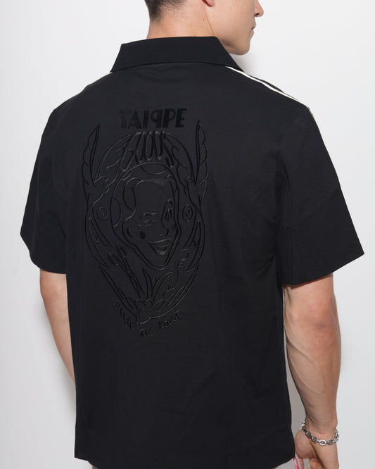 Person wearing a black polo with a logo and text on a white background