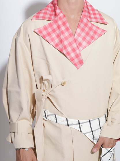 Person wearing a beige trench coat with a pink gingham collar