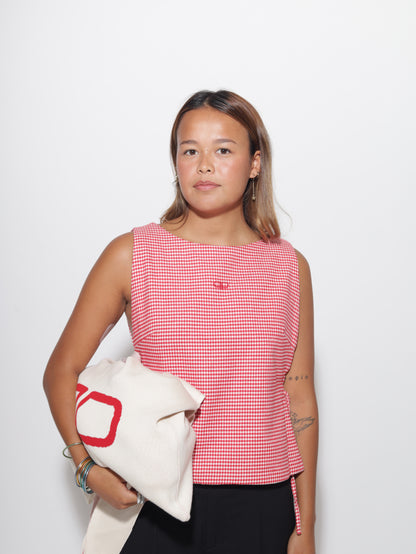 Woman wearing a red and white checkered vest on a white background