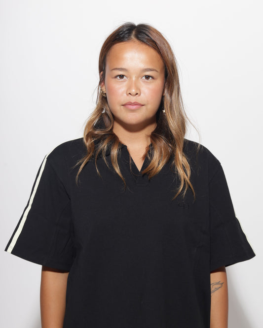 Person wearing a black t-shirt with a yellow stripe on a plain background