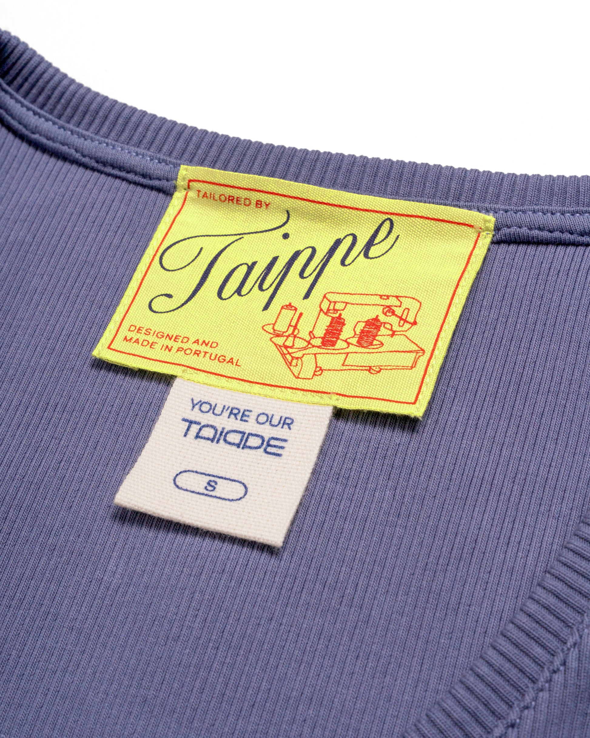 Close-up of a blue tank top with a yellow tag featuring the brand 'Taippe'.