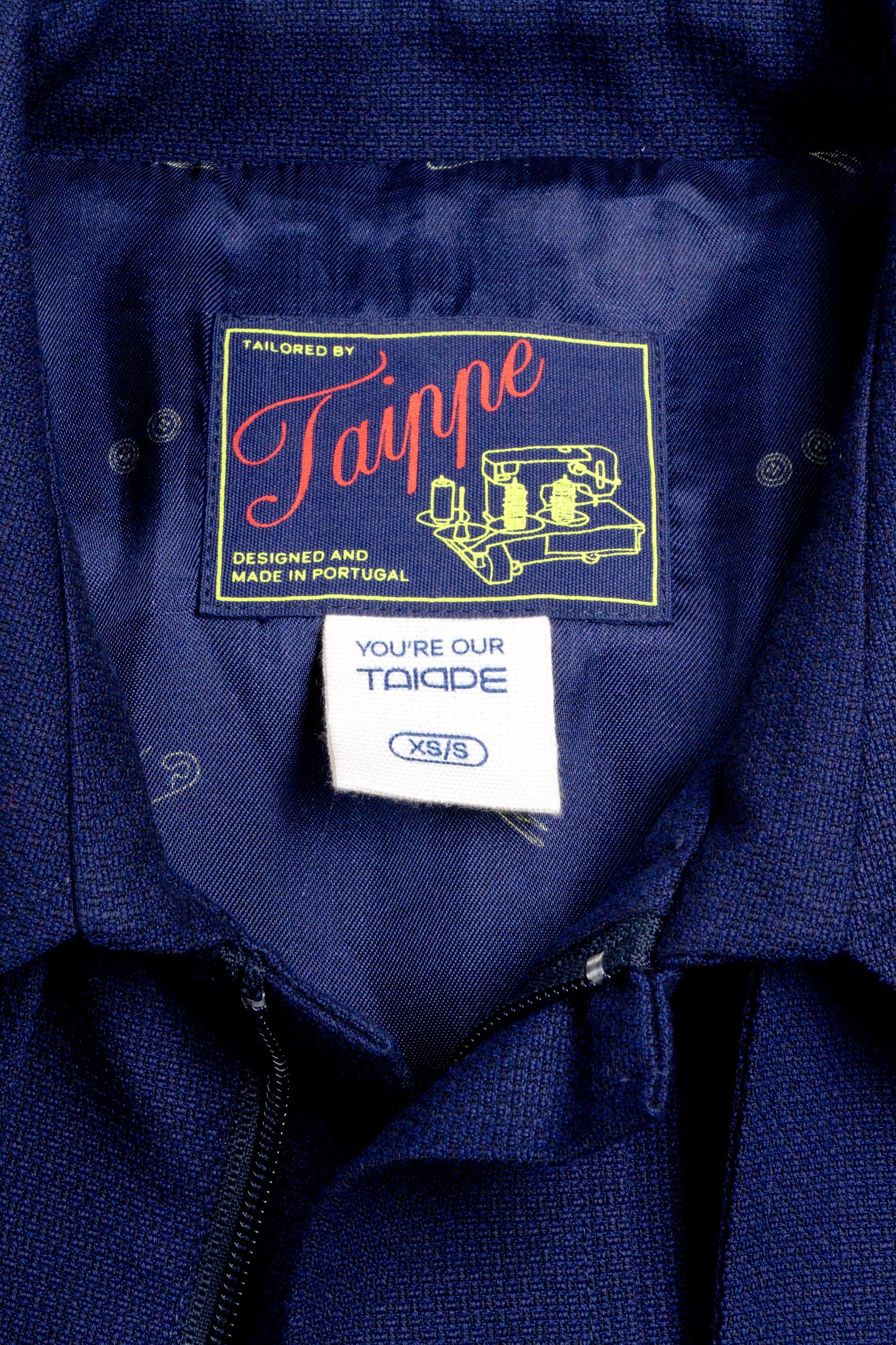 Close-up of a navy blue coat with 'Taippe' branding on a label.
