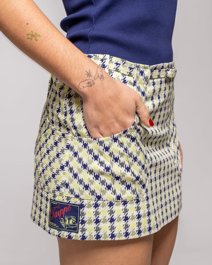 Person wearing a checkered skirt with a visible brand logo on a plain background