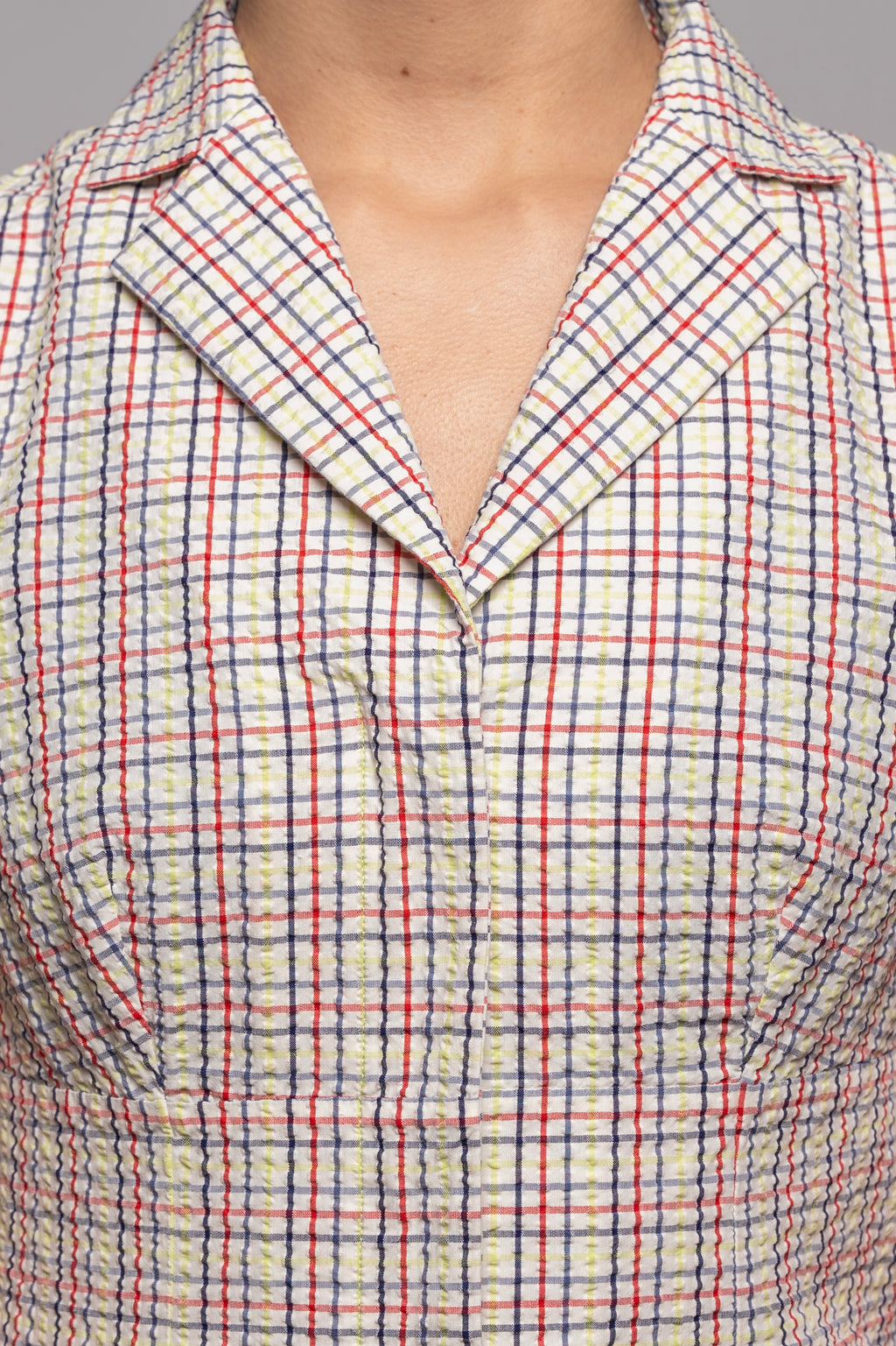 Close-up of a person wearing a plaid blouse with red and blue lines 