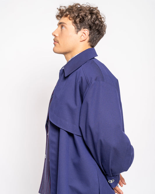 Person wearing a long blue coat against a white background
